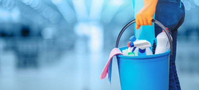 A lady standing with a bucket and cleaning products