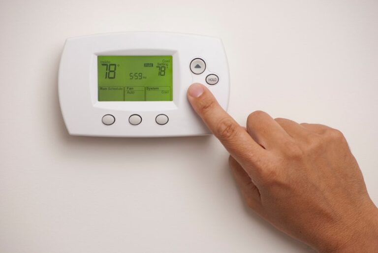 finger pressing button on thermostat